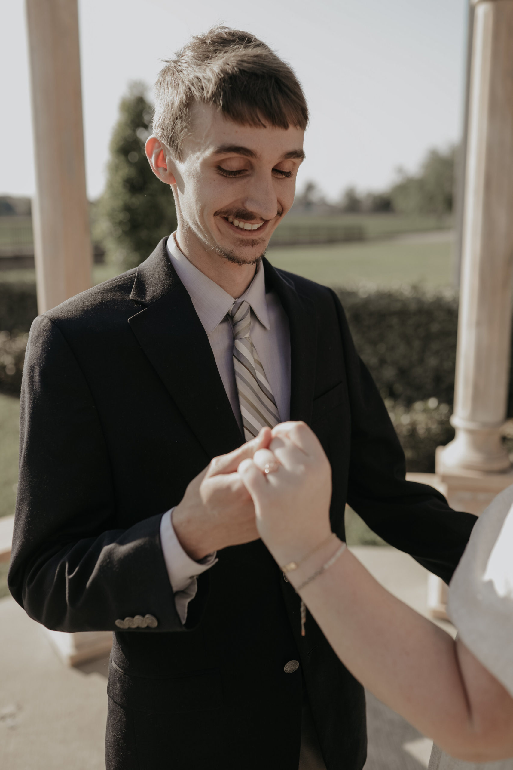 guy holding his fiancè's hand, looking at her hand with a new ring. under a gazebo, engagement photos, wedding photography