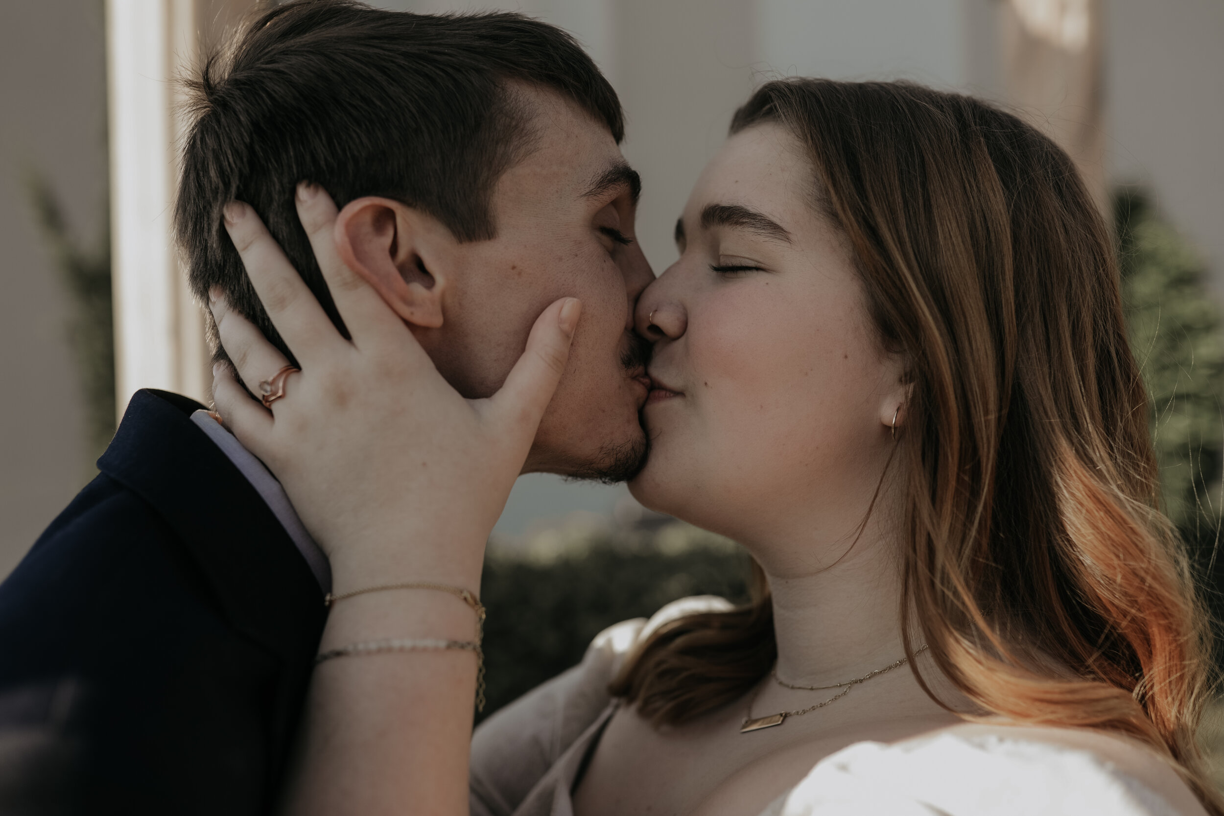 couple kissing under a gazebo, engagement, a wedding band on her hand which is cupping the side of his face. engagement photos, proposal photos